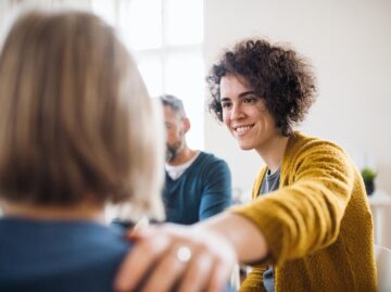 woman offering support to another woman in group therapy